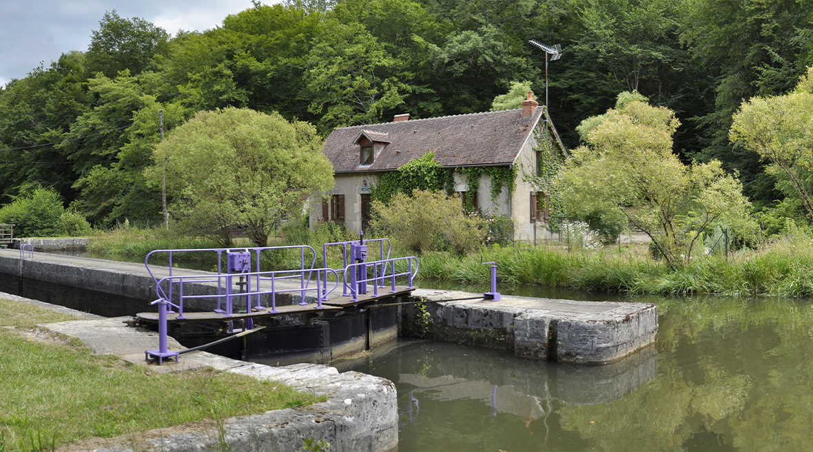 canal lock with greenery all around and small French house